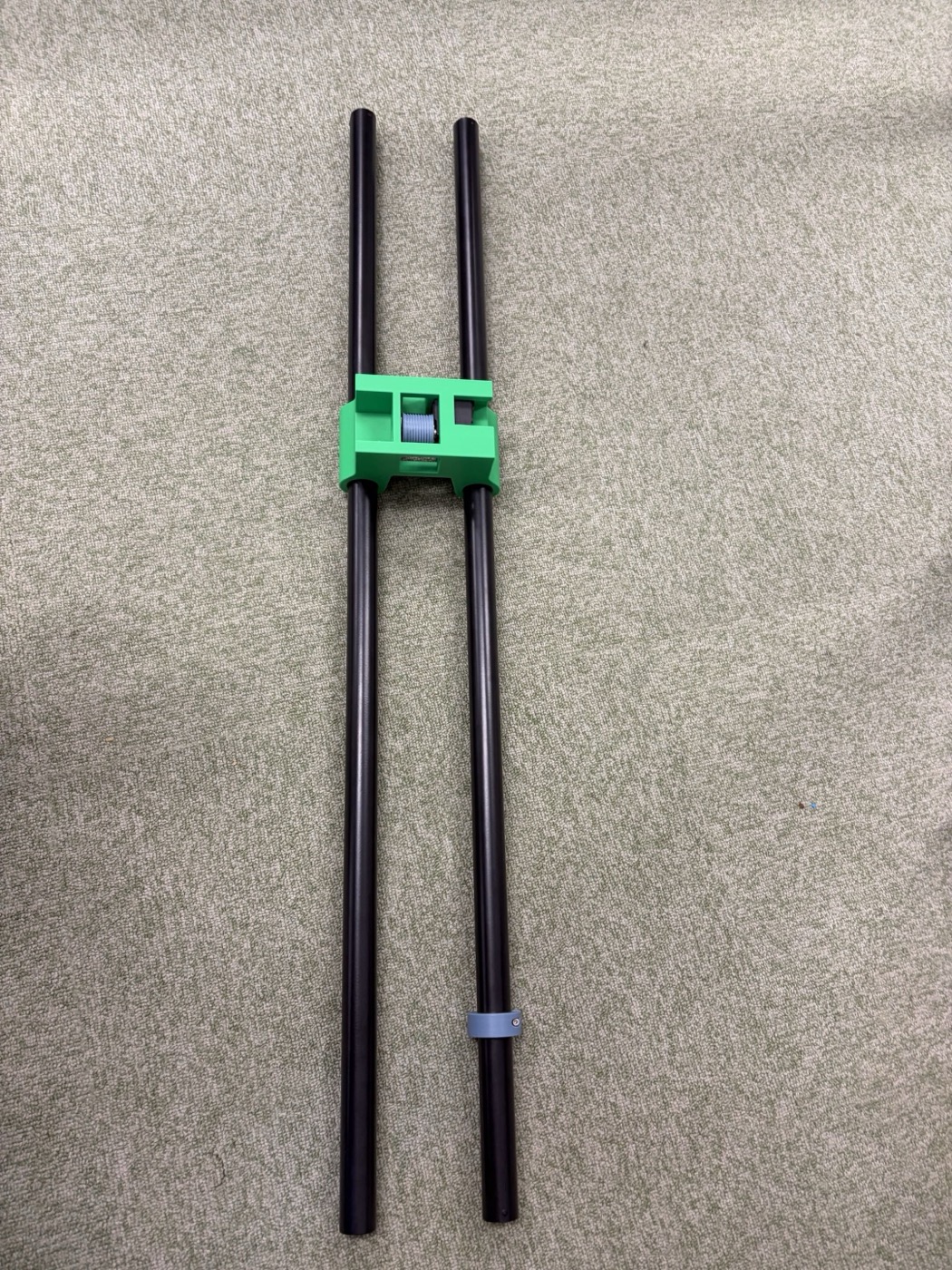 2本の黒いポールに緑色の3Dプリントマウントが取り付けられ、その中に糸が巻かれた小さな軸が収まっている。下側のポールには青いリング状の部品も取り付けられている